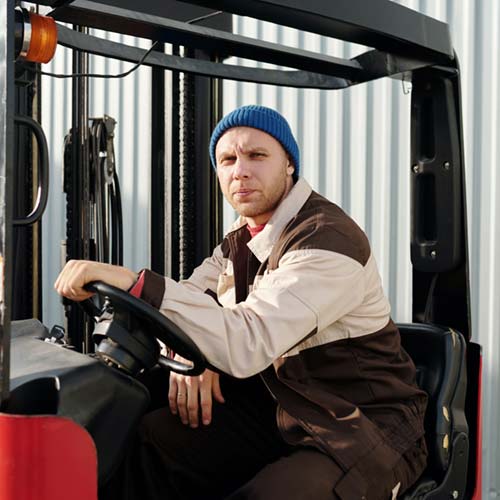 A worker seated at the wheel of a forklift
